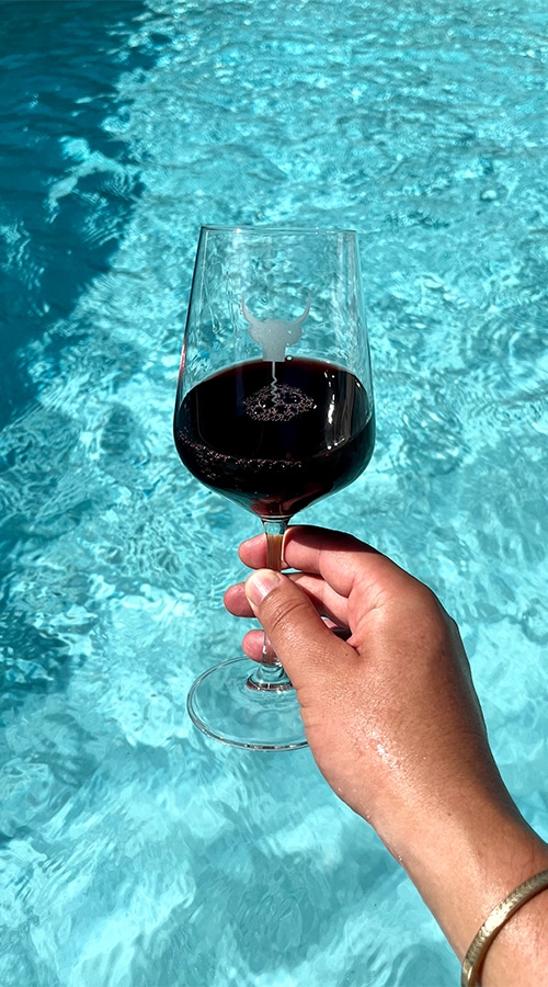 Glass of red wine by the pool